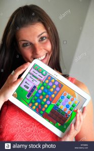 france-young-woman-playing-candy-crush-on-her-tablet-HPG88G.jpg